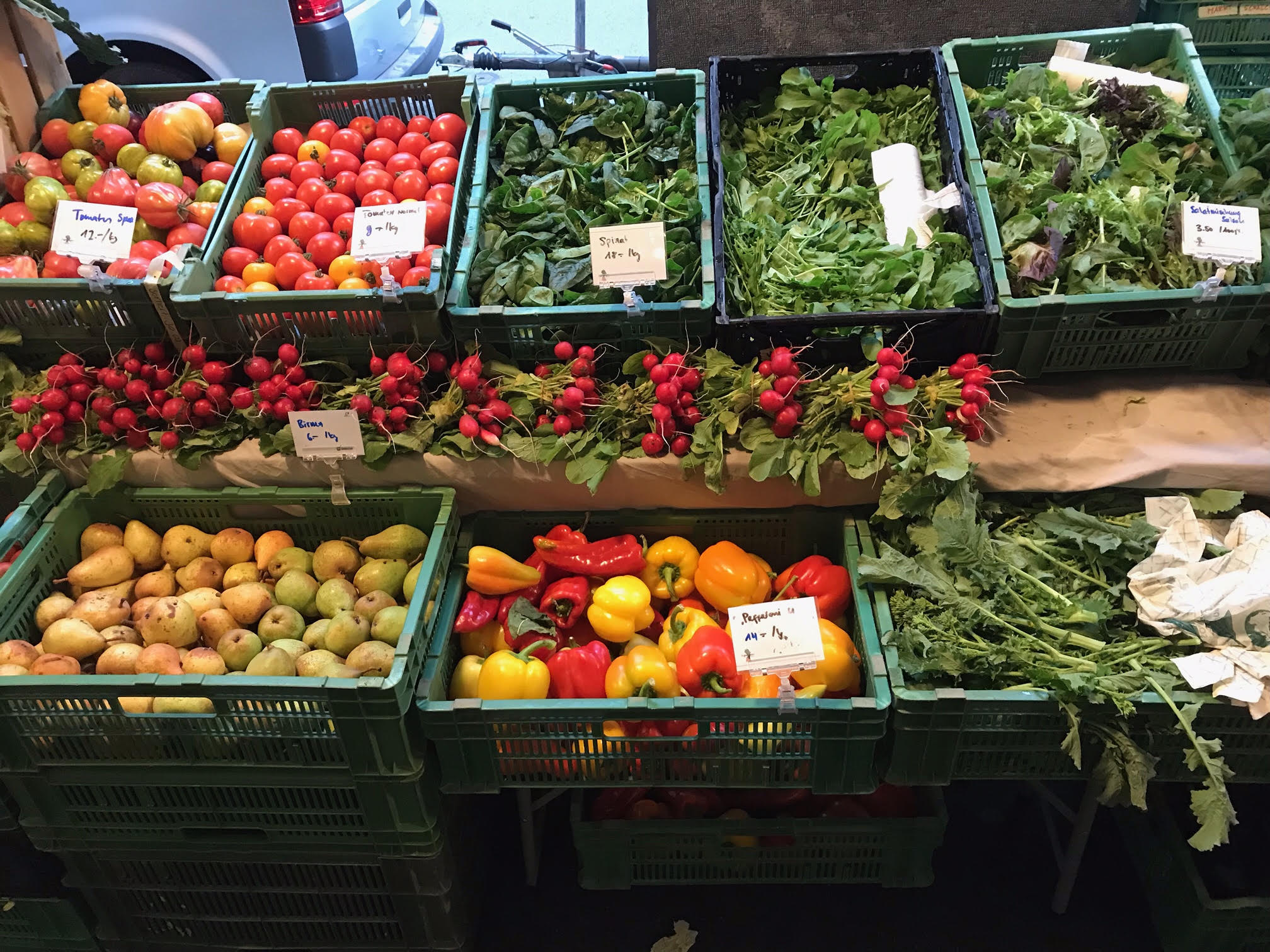 Farbenfroher Marktstand mit Radieschen, Peperoni und Tomaten